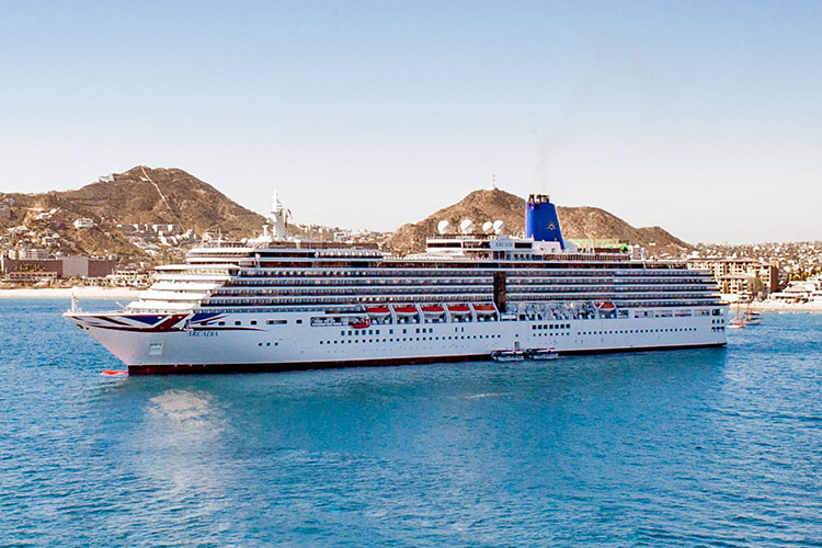 Cruise Ship in the ocean with mountains in the background.